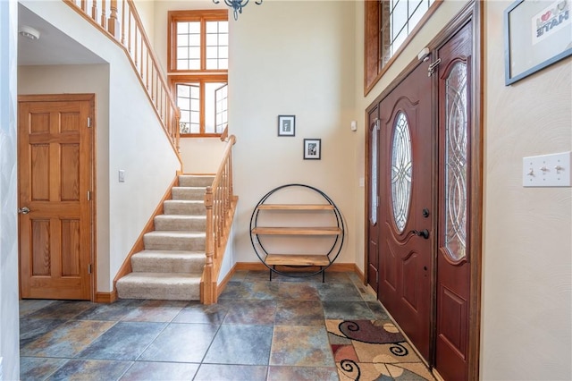 entryway featuring stairway, stone finish floor, and baseboards