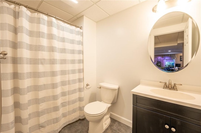 bathroom featuring a drop ceiling, tile patterned flooring, toilet, vanity, and baseboards