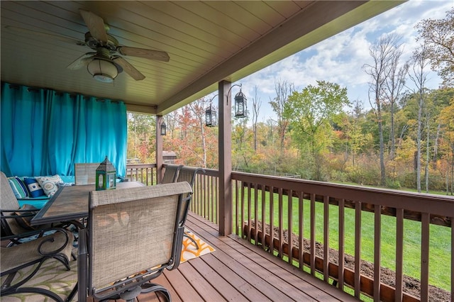 wooden terrace featuring a yard, a ceiling fan, and outdoor dining space