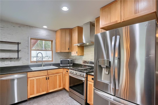 kitchen with dark countertops, wall chimney exhaust hood, appliances with stainless steel finishes, and a sink