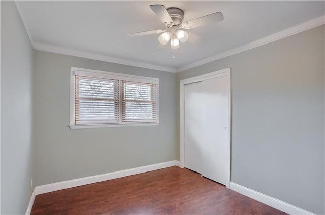 unfurnished bedroom with a closet, crown molding, baseboards, and wood finished floors