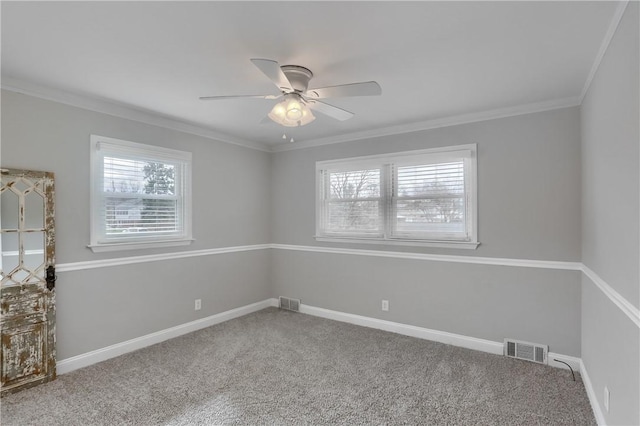 carpeted spare room with ceiling fan, ornamental molding, visible vents, and baseboards