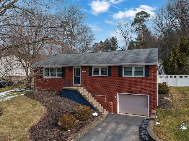 ranch-style house with aphalt driveway, brick siding, fence, and a garage