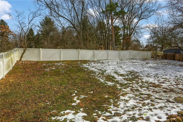 snowy yard featuring a fenced backyard