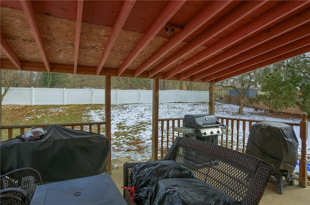 snow covered deck featuring a fenced backyard and area for grilling