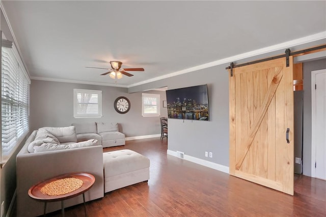 living room with ceiling fan, a barn door, dark wood-style flooring, baseboards, and ornamental molding