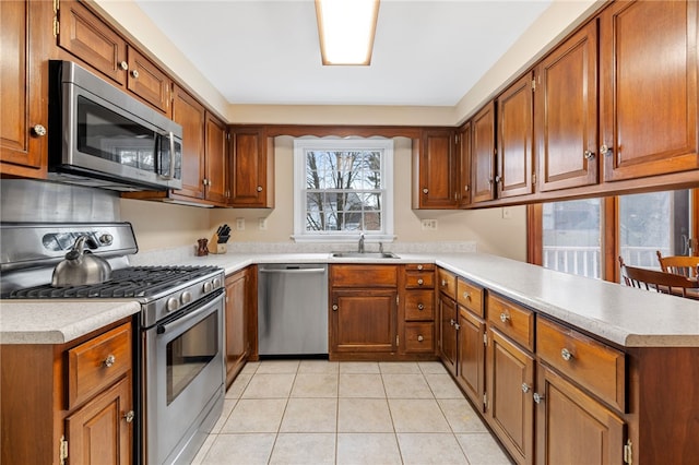 kitchen with stainless steel appliances, brown cabinets, light countertops, and a peninsula