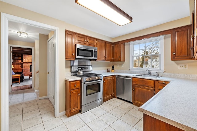 kitchen with light countertops, appliances with stainless steel finishes, brown cabinetry, and a sink