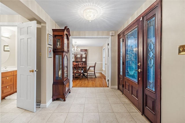 entryway featuring light tile patterned floors, baseboards, and an inviting chandelier