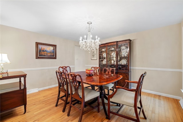 dining space featuring light wood-style floors, visible vents, baseboards, and a chandelier