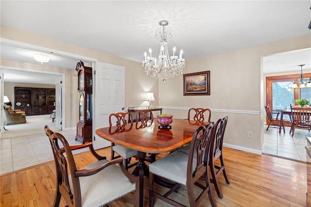 dining room with a chandelier, light wood-style flooring, and baseboards