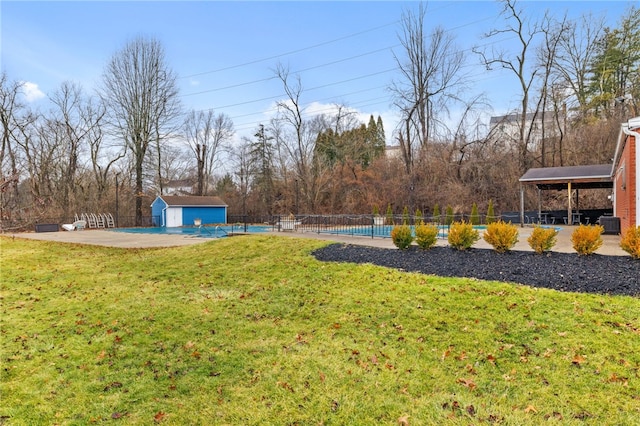 view of yard featuring a patio, an outdoor structure, fence, and a fenced in pool