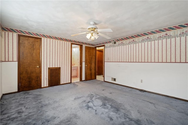 carpeted spare room featuring a ceiling fan, visible vents, baseboards, and wallpapered walls