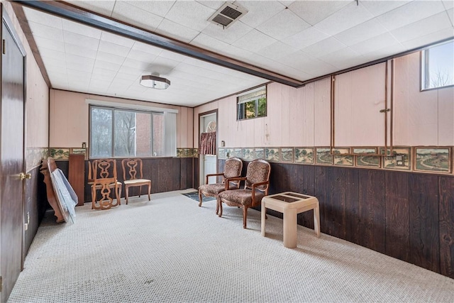 sitting room featuring carpet floors, a wainscoted wall, visible vents, and wood walls