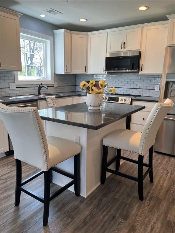 115 White Fox Ct Unit 33, North Sewickley Twp, PA 16117 - kitchen with appliances with stainless steel finishes, a kitchen bar, decorative backsplash, dark wood-style floors, and recessed lighting