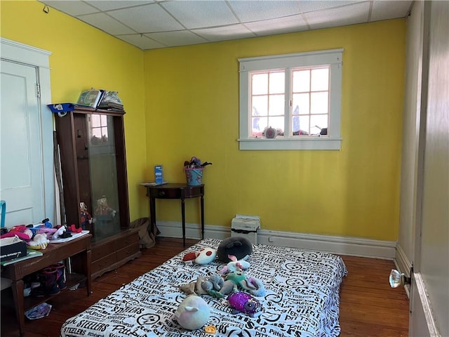 misc room with a paneled ceiling, baseboards, and wood finished floors