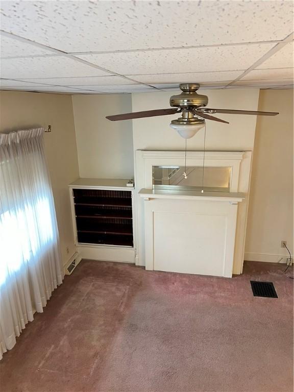 unfurnished living room featuring ceiling fan, visible vents, carpet, and a paneled ceiling