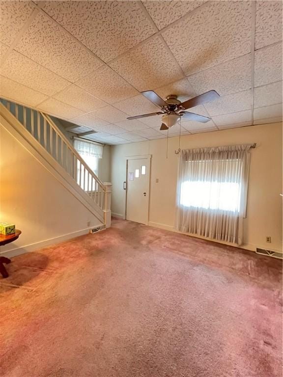 unfurnished living room with carpet floors, a paneled ceiling, visible vents, baseboards, and stairs