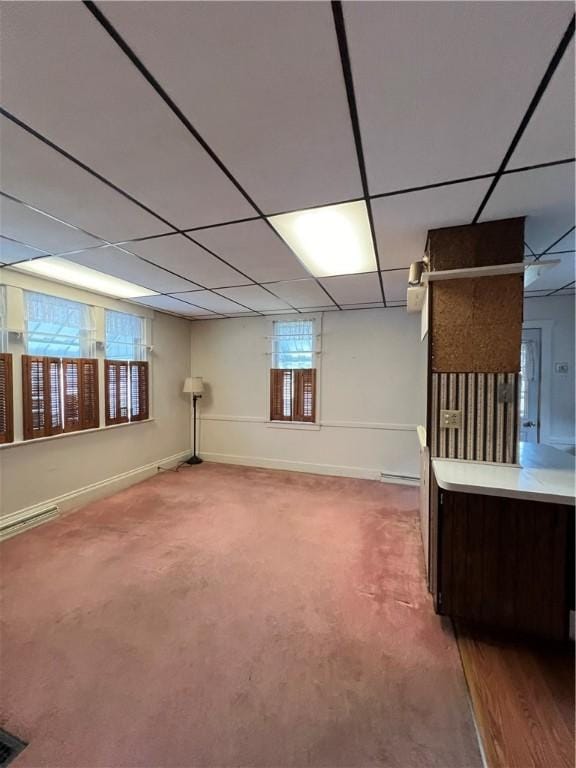 basement featuring carpet flooring, a paneled ceiling, and baseboards