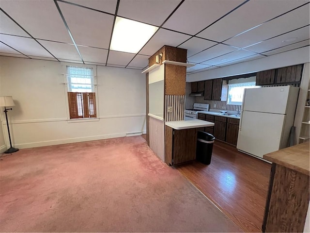 kitchen featuring a wealth of natural light, light countertops, white appliances, and dark brown cabinetry