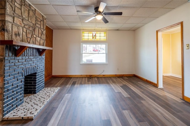 unfurnished living room with dark wood finished floors, a drop ceiling, and a fireplace