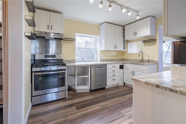 kitchen featuring light stone counters, under cabinet range hood, stainless steel appliances, a sink, and white cabinetry