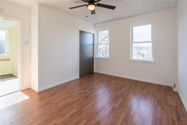 unfurnished room with visible vents, ceiling fan, baseboards, and wood finished floors