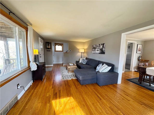 living area featuring a wealth of natural light, wood finished floors, visible vents, and baseboards