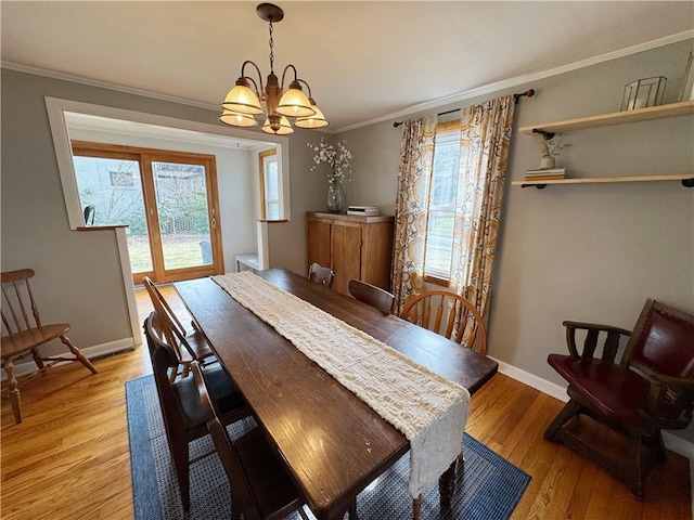 dining room with baseboards, ornamental molding, light wood-type flooring, and a notable chandelier