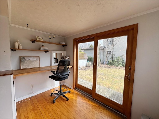 office space featuring a textured ceiling, hardwood / wood-style flooring, baseboards, ornamental molding, and built in study area