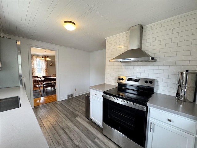 kitchen featuring wood finished floors, visible vents, appliances with stainless steel finishes, decorative backsplash, and wall chimney exhaust hood