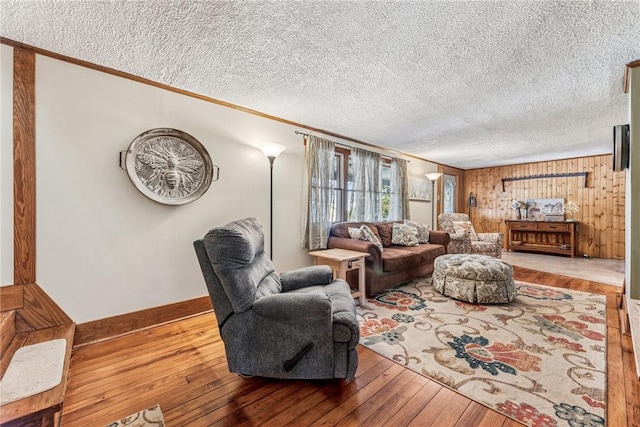 living area with ornamental molding, baseboards, a textured ceiling, and hardwood / wood-style floors