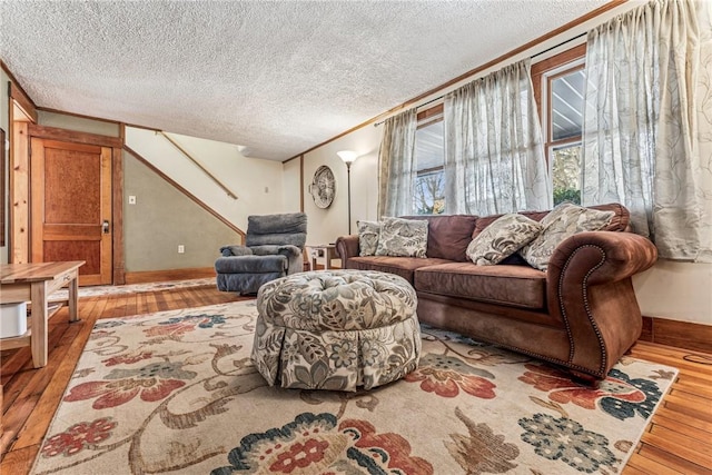 living area with a textured ceiling, ornamental molding, wood-type flooring, and baseboards