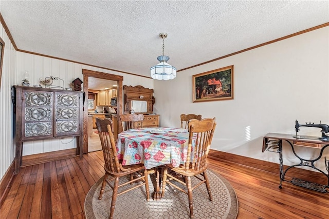 dining room featuring crown molding, a textured ceiling, and hardwood / wood-style floors