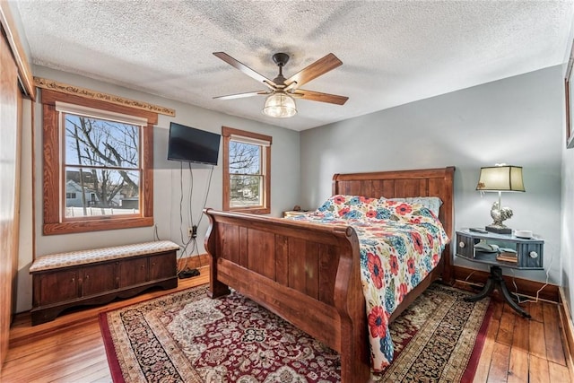 bedroom featuring wood-type flooring, baseboards, ceiling fan, and a textured ceiling