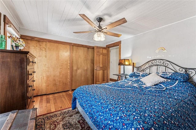 bedroom featuring a ceiling fan, wood ceiling, wood-type flooring, and a closet