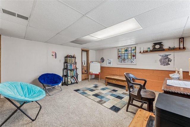 carpeted office space with a drop ceiling, visible vents, and concrete block wall