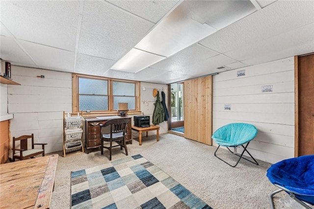 office area featuring a paneled ceiling, carpet flooring, and wood walls