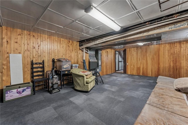 finished basement featuring dark colored carpet and wood walls