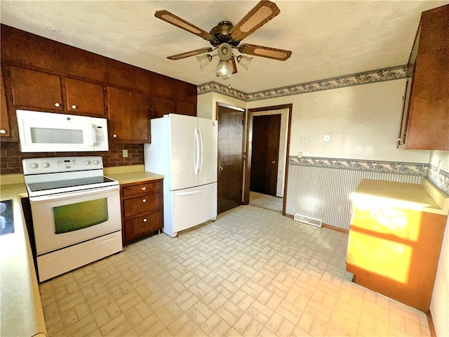 kitchen with white appliances, wainscoting, ceiling fan, light countertops, and brick patterned floor