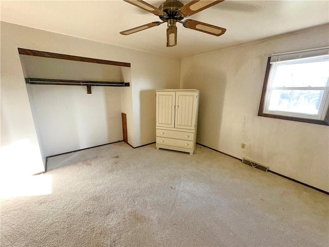 unfurnished bedroom featuring a ceiling fan, light colored carpet, a closet, and visible vents