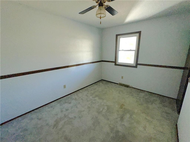 spare room featuring visible vents, a ceiling fan, and light colored carpet