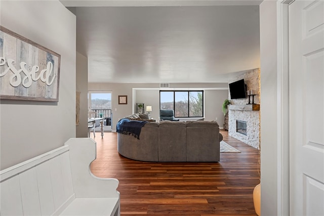 living area featuring a healthy amount of sunlight, a fireplace, visible vents, and dark wood-type flooring