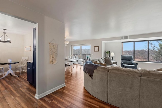 living area featuring visible vents, dark wood finished floors, and an inviting chandelier