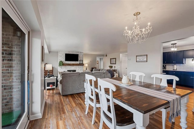 dining area with light wood-style floors, a fireplace, and an inviting chandelier