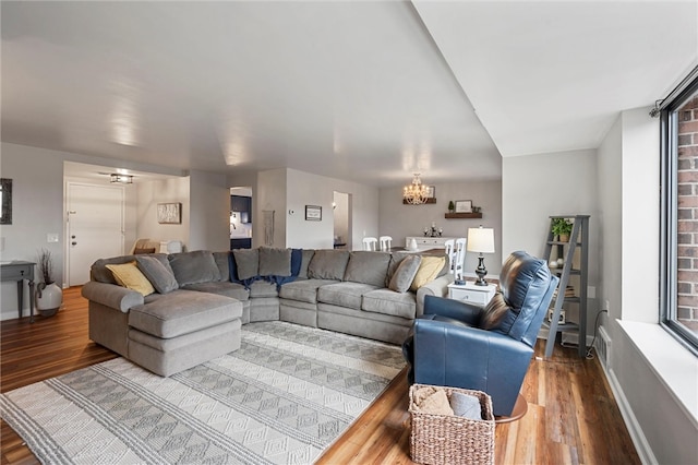 living room featuring baseboards, a chandelier, and wood finished floors