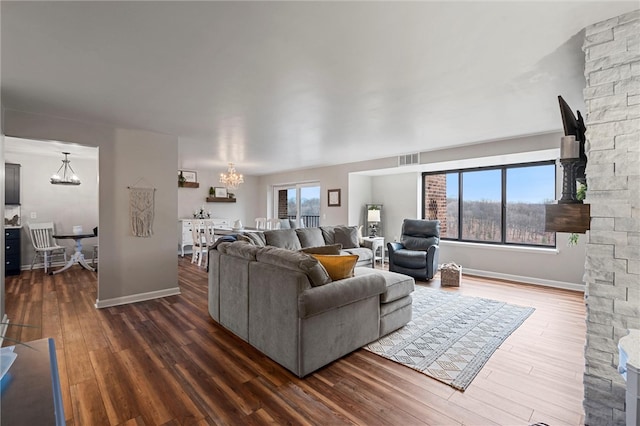 living room with a chandelier, dark wood-style floors, visible vents, and baseboards