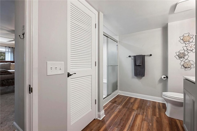 bathroom with baseboards, toilet, wood finished floors, vanity, and a shower stall