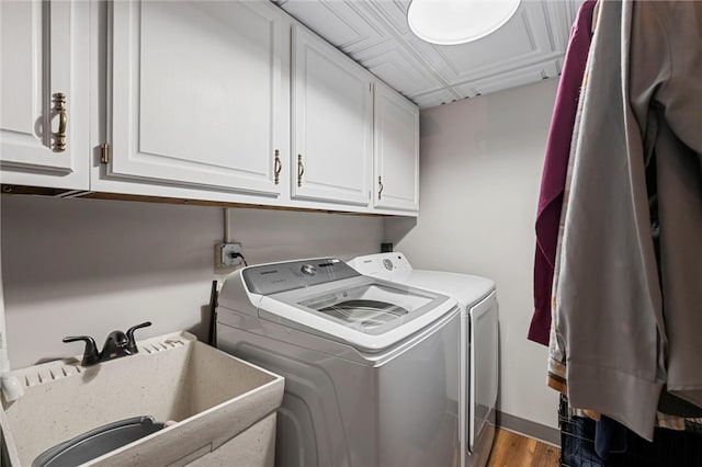 laundry room featuring cabinet space, wood finished floors, a sink, and washing machine and clothes dryer