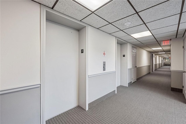 hallway with baseboards, carpet flooring, a paneled ceiling, and elevator